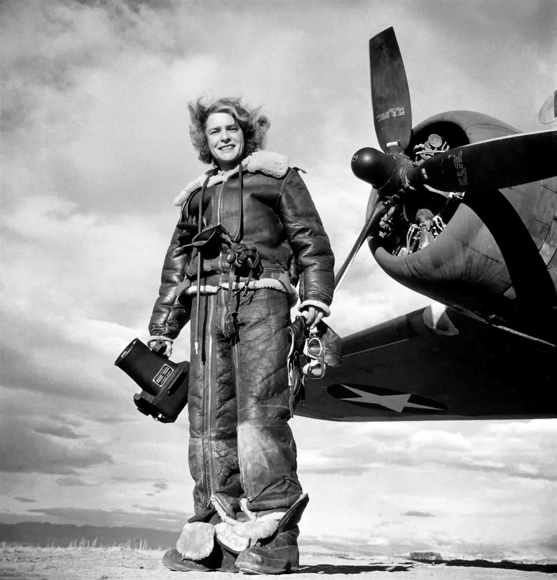 Autore sconosciuto, <i>La fotografa di LIFE, Margaret Bourke-White, vestita con una tuta di volo in pile e con la macchina fotografica aerea in mano, in piedi davanti al bombardiere Flying Fortress dal quale ha realizzato fotografie di guerra durante l’attacco statunitense su Tunisi. Algeria</i>, 1943<br>Margaret Bourke-White/The LIFE Picture Collection/Shutterstock 