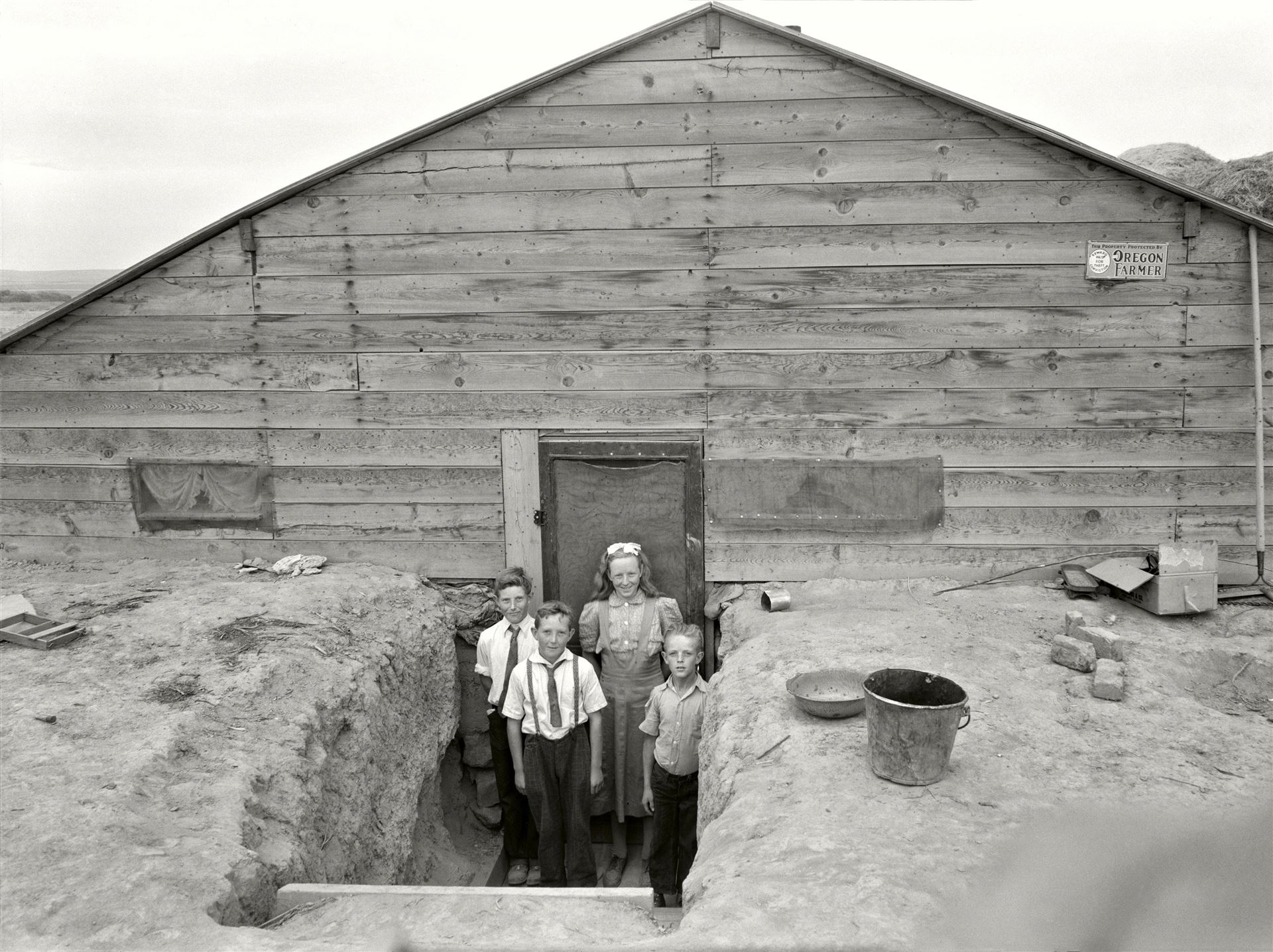 <div>Dorothea Lange, <i>Bambini della famiglia Free all'ingresso della loro casa, in abiti domenicali</i>, Dead Ox Flat, Malheur County, Oregon, 1939</div><div>© Dorothea Lange</div>